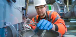 Im Wasserwerk Grimma hält ein Mitarbeiter eine Karaffe mit Wasser in der Hand.